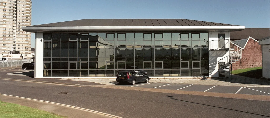 Curved standing seam metal roof with a glazed facade on a commercial building completed by JGL Roofing
